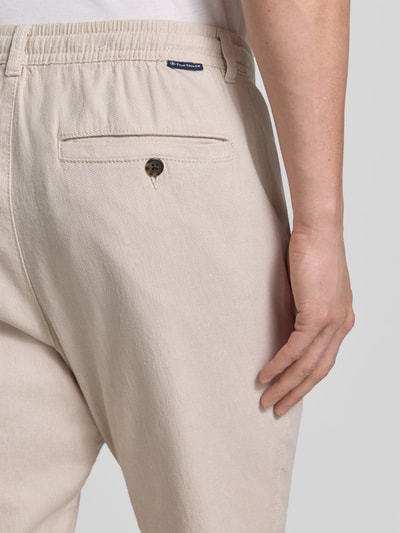 Mężczyzna nosi Regular Fit Chino aus Baumwoll-Mix von Tom Tailor, beżowy melanż, detal tylnej kieszeni, bawełniany miks, krój regular fit, label patch, szlufki na pasek, zapięcie na guzik i kryty zamek, tylne oraz boczne kieszenie, widok z tyłu, zbliżenie na górę.
