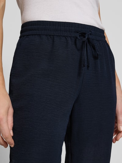 Frauenmodel trägt Jogpants mit elastischem Bund und Eingrifftaschen von Christian Berg Woman in Dunkelblau, Slim Fit, Kordelzug, Nahaufnahme Oberkörper