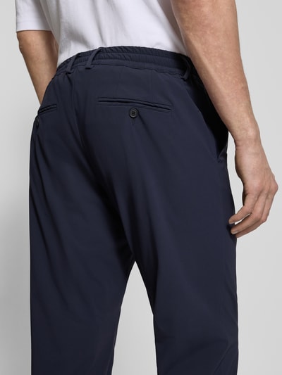 Männermodel trägt Slim Fit Hose mit Paspeltaschen am Gesäß von CRUNA in Dunkelblau, Material-Mix mit Stretch-Anteil, Detailaufnahme Rückansicht.