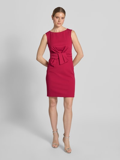 Frauenmodel trägt Knielanges Cocktailkleid mit Knotendetail von Vera Mont in Pink, Material-Mix mit Stretch-Anteil, Gerader-Schnitt, Rundhalsausschnitt, Ganzkörperansicht von vorne.