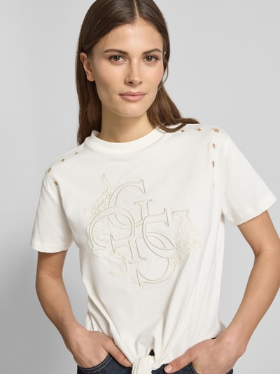 Frauenmodel trägt Regular Fit T-Shirt mit Lochmuster von Guess, Reine Baumwolle, Logo-Stitching, Rundhalsausschnitt, weiß, Nahaufnahme Oberkörper.