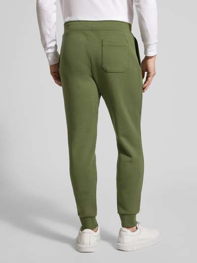 Męski model nosi Tapered Sweatshorts aus Baumwoll-Mix von Polo Ralph Lauren, zielony, krój tapered, logo, kieszenie, widok całej sylwetki z tyłu.