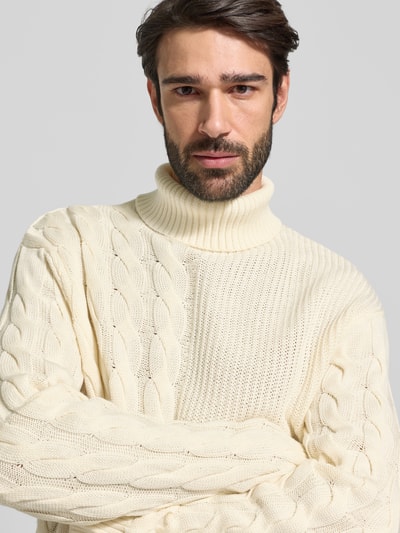 Męski model nosi Regular Fit Rollkragenpullover aus Baumwoll-Mix od Tom Tailor Denim, kremowy sweter w warkoczowy wzór, dzianina, zbliżenie na górną część ciała.