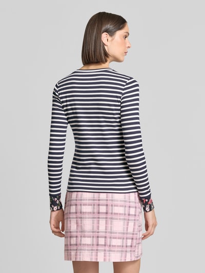 Kobiece modelka ma na sobie Slim Fit Longsleeve aus Baumwoll-Mix von Marc Cain, mieszanka bawełny, krój slim fit, okrągły dekolt, kwiatowe detale, długość tyłu w rozmiarze 36: 57 cm, widok na całe ciało od tyłu.