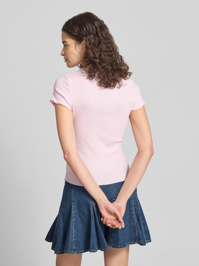Frauenmodel trägt Slim Fit T-Shirt aus Baumwoll-Mix von Tommy Hilfiger in Hellrosa mit Frill-Ärmeln und Rundhals zu Jeansrock, Ganzkörperansicht Rückansicht.