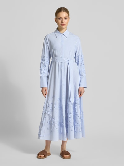 Frauenmodel trägt Hemdblusenkleid mit verdeckter Knopfleiste und Bindegürtel von Marc Cain, Baumwoll-Mix mit Stretch-Anteil, Taillierter Schnitt, Midikleid, Hemdblusenkragen, Rückenlänge bei Größe 36: 130 cm, Brustweite bei Größe 36: 54 cm, Ärmellänge bei Größe 36: 60 cm, hellblau mit weißen Streifen, florale Strukturmuster, fließende Stoff-Textur, Ganzkörperansicht von vorne.