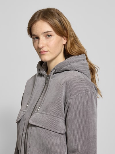 Frauenmodel trägt Regular Fit Bomberjacke mit Kapuze Modell 'SUVA' von Only aus grauem Cord, gestreifte Struktur, Label Stitching, Nahaufnahme Oberkörper.