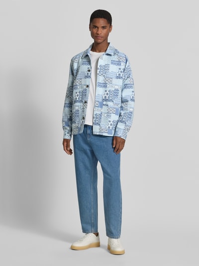 Męski model nosi Regular Fit Overshirt im Allover-Look od Les Deux, bawełniany miks, krój regular fit, wzór allover, kołnierzyk kent, zapięcie na guziki, długość tyłu w rozmiarze M: 69 cm, jasnoniebieskie odcienie, geometryczne motywy, gładka tekstura, widok całej sylwetki z przodu.