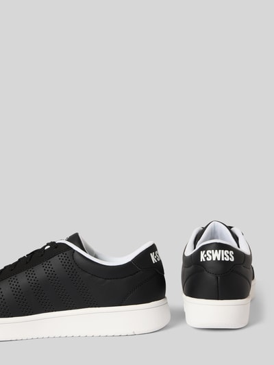 Produktfoto, Sneaker mit Label-Print Modell 'COURT' von K-Swiss in Schwarz mit weißer Sohle, Lochmuster, seitliche und rückseitige Ansicht