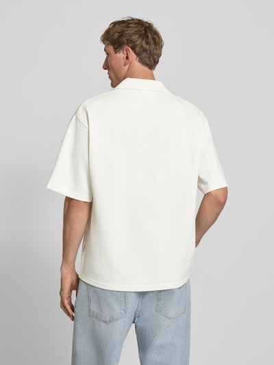 Männermodel trägt Regular Fit Poloshirt mit Logo Modell 'Eddie' von Redefined Rebel aus Baumwoll-Mix in Creme, Rückenlänge bei Größe M 73 cm, Ganzkörperansicht Rückansicht.