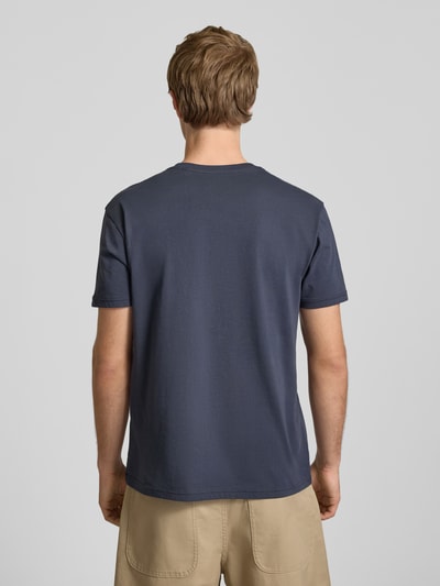 Männermodel trägt T-shirt mit logo en ronde hals van Alpha Industries, puur katoen, regular fit, ruglengte bij maat M 67 cm, Ganzkörperansicht Rückansicht.