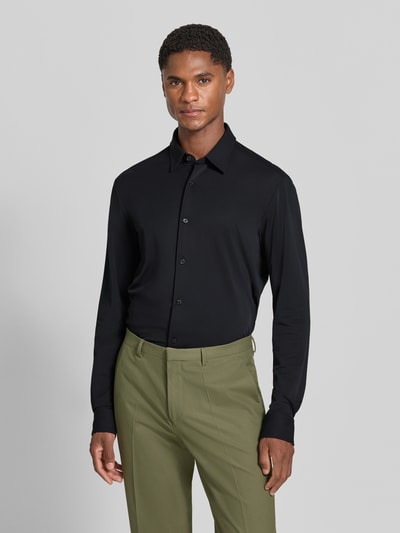 Männermodel trägt schwarzes Slim Fit Businesshemd mit Kentkragen Modell 'P-Roan' von BOSS zu olivgrüner Hose, Ganzkörperansicht von vorne, Herren Businesshemd von BOSS.