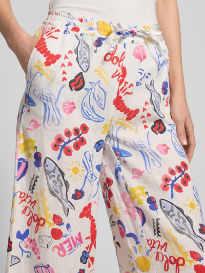 Frauenmodel trägt Wide Fit Leinenhose mit Allover-Motiv-Print von Christian Berg Woman, bunte Farben, elastischer Bund, Nahaufnahme Oberkörper.