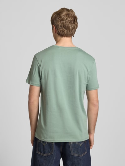 Männermodel trägt T-Shirt mit Logo und Rundhalsausschnitt von Alpha Industries in Grün, Reine Baumwolle, Regular-Fit, Rückenlänge 67 cm, Ganzkörperansicht Rückansicht.