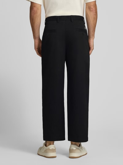 Männermodel trägt Loose Fit Weite Hose aus Baumwoll-Mix von Lacoste in Schwarz, glatte Oberfläche, Herren Weite Hose. Ganzkörperansicht Rückansicht.