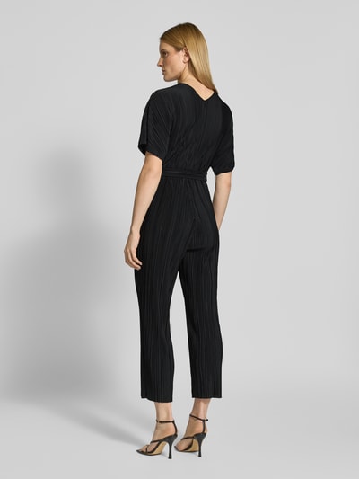 Vrouwenmodel draagt Regular Fit Jumpsuit met V-hals model 'Olinda' van YAS, getailleerde pasvorm, plissélook, afneembare stoffen riem, korte mouwen, zwart, volledige lichaamsweergave achteraan.