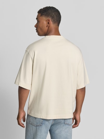 Männermodel trägt Boxy Fit T-Shirt aus reiner Baumwolle Modell 'CORY' von Selected Homme in Beige, schlichte Optik, Ganzkörperansicht Rückansicht. Herren T-Shirt von Selected Homme