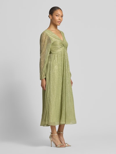Frauenmodel trägt Tailliertes Freizeitkleid mit Unterkleid von s.Oliver BLACK LABEL in grüner Metallic-Optik, Langarm, Midi-Länge, Crinkle-Optik, tiefer V-Ausschnitt, Materialverarbeitung Crinkle, Ganzkörperansicht von vorne.