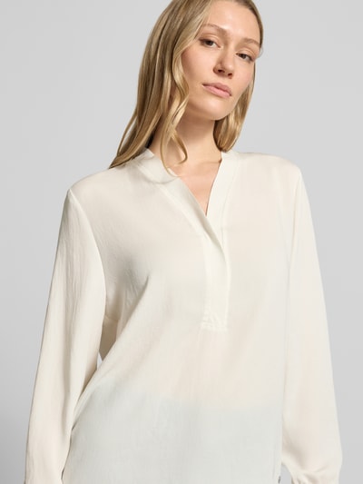 Frauenmodel trägt Bluse mit V-Ausschnitt und Label-Detail von Marc Cain in Creme mit elastischen Ärmelabschlüssen, Loose Fit, Nahaufnahme Oberkörper.