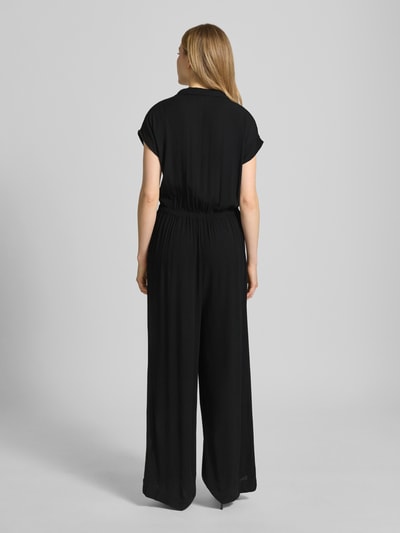 Modelka kobieca nosi czarny Jumpsuit aus Viskose mit V-Ausschnitt Modell 'MARRAKECH' od ICHI, gładka tkanina, krój slim fit, widok całej sylwetki z tyłu.
