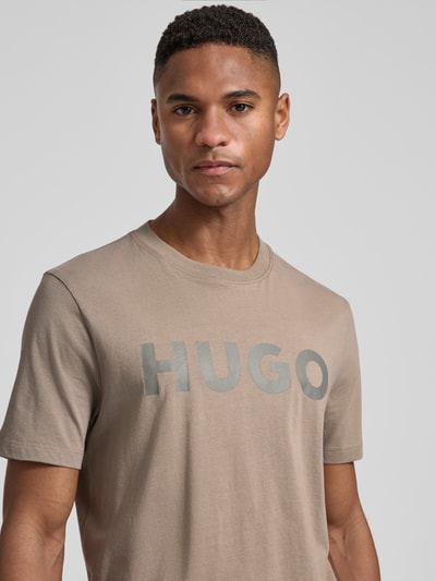 Männermodel trägt Relaxed Fit T-Shirt aus reiner Baumwolle Modell 'DULIVIO' von HUGO, Optik: Unifarben, Label-Schriftzug, Nahaufnahme Oberkörper.