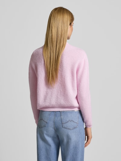 Vrouwenmodel draagt Strickjacke mit Knopfleiste Modell 'VITOW' van American Vintage in lichtroze, grof gebreid, geribde boorden, losse pasvorm, rugaanzicht volledige lichaamsweergave.