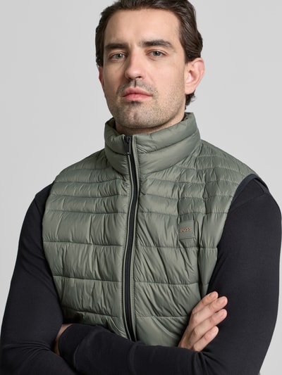 Männermodel trägt Regular Fit Steppweste mit Stehkragen Modell 'ODENO2' von BOSS Orange, Label Patch, unifarben, Nahaufnahme Oberkörper.