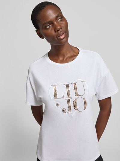 Vrouwenmodel draagt Regular Fit T-shirt met strass-steentjes van Liu Jo White, puur katoen, logodetail, ronde hals, nahaufnahme bovenlichaam.