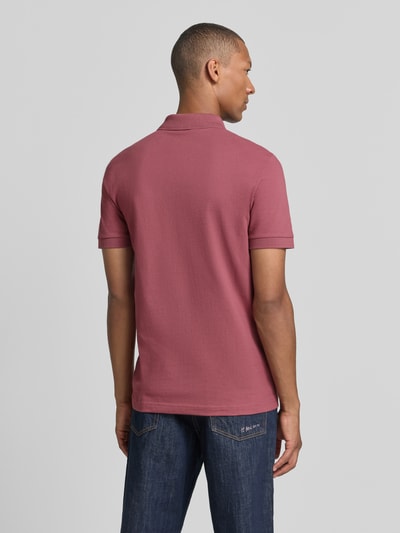 Männermodel trägt Regular Fit Poloshirt aus Baumwoll-Mix Modell 'Passenger' von BOSS Orange in Altrosa, glatte Struktur, Ganzkörperansicht Rückansicht.