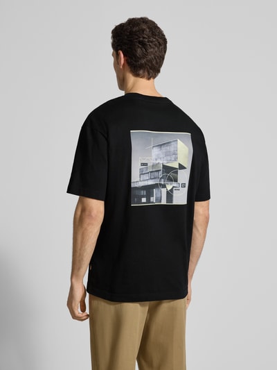 Männermodel trägt Regular Fit T-Shirt aus reiner Baumwolle Modell 'TE-BRUTALISM' von BOSS Orange, Schwarz, Grafikdruck, Rückansicht.