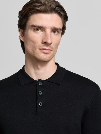 Männermodel trägt Strickpullover mit Polokragen Modell 'FRODE' von Casual Friday, schwarz, feine Strickstruktur, Nahaufnahme Oberkörper. Baumwoll-Kaschmir-Mix, Regular Fit, kurze Knopfleiste, gerippte Abschlüsse.