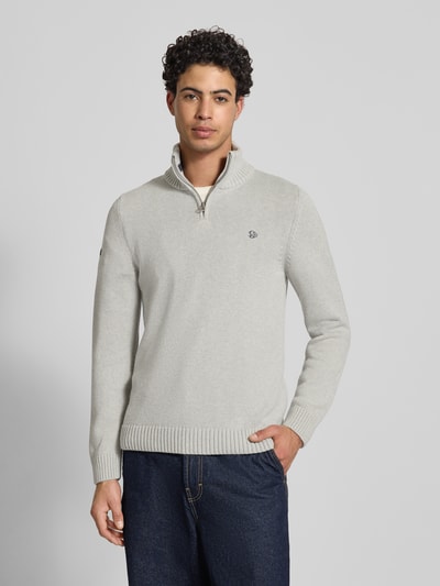 Męski model nosi Slim Fit Pullover in Strick-Optik od Superdry, kolor jasnoszary, stójka, zamek błyskawiczny, wyhaftowane logo, długość tyłu w rozmiarze M 70 cm, długość rękawa 65 cm, imitacja dzianiny, krój slim fit, całkowity widok z przodu.
