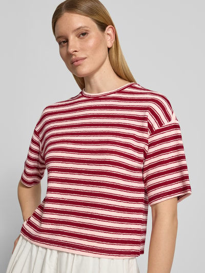 Frauenmodel trägt Oversized T-Shirt mit Strukturmuster Modell 'Cessalia' von MSCH Copenhagen, Rundhalsausschnitt, Damen T-Shirt, gestreift in Rot und Rosa, Oversized-Fit, Rückenlänge bei Größe XS/S 53 cm, Nahaufnahme Oberkörper.