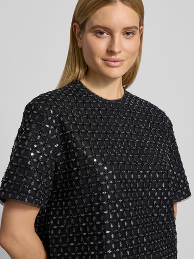Frauenmodel trägt Oversized T-Shirt mit Ziersteinen von ROTATE mit Allover-Pailettenbesatz, Rundhalsausschnitt, Kurzärmelig, Nahaufnahme Oberkörper.