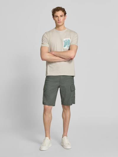 Männermodel trägt Relaxed Fit Cargoshorts aus Leinen-Mix Modell 'SISLA-CARGO-S1' von BOSS Orange, Optik: Unifarben, Materialverarbeitung: Popeline, Label-Schriftzug, seitliche Eingrifftaschen, Cargotaschen, Knopf und verdeckter Reißverschluss, Ganzkörperansicht von vorne.