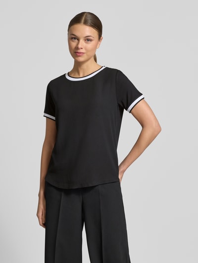 Modelka nosi Regular Fit T-Shirt aus Viskose-Mix von More & More, czarny kolor, elastyczny materiał, krój regular fit, okrągły dekolt, krótkie rękawy, długość tyłu w rozmiarze 36: 57 cm, ujęcie całej sylwetki z przodu.