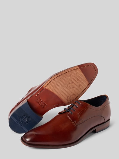 Produktfoto, Derby aus Leder mit Schnürung Modell 'Milko' von Bugatti in Braun, mit abgerundete Spitze, Label-Detail, Absatzhöhe 2 cm, Schafthöhe 7 cm, Schaftweite 11 cm, glatte Textur.