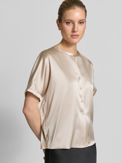 Modelka kobieca ma na sobie Relaxed Fit Seidenbluse mit Rundhalsausschnitt od HERZENS, jasny beż, jedwabna mieszanka, rozpinana, krótki rękaw, długość tyłu 63 cm, długość rękawa 18 cm, widok całej sylwetki z przodu.