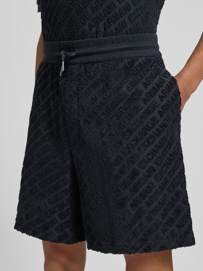 Männermodel trägt Shorts mit Logo-Muster und elastischem Bund von ARMANI EXCHANGE, katoen-elastaanmix, regular fit, zwart, logo patroon, elastische tailleband, geheelopname voorkant