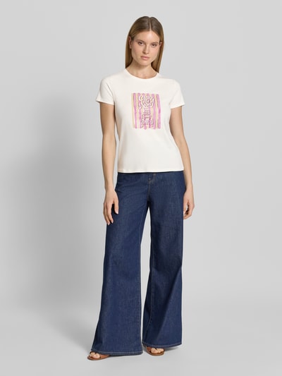 Frauenmodel trägt T-Shirt mit Motiv-Print und Rundhalsausschnitt von Zero in Weiß mit rosa Muster, gerade geschnitten, Ganzkörperansicht von vorne.