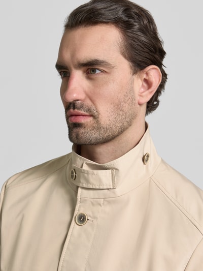 Männermodel trägt Mantel mit durchgehender Knopfleiste von CINQUE in Beige, Stehkragen mit Riegel, Nahaufnahme Oberkörper. Rückenlänge bei Größe 50: 83 cm, Schulterbreite: 42 cm, Brustweite: 40 cm, Ärmellänge: 66 cm.