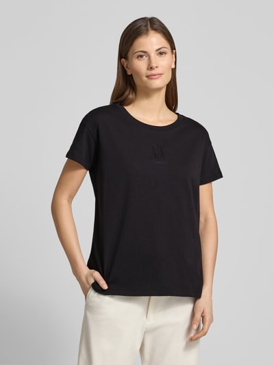 Frauenmodel trägt T-Shirt aus reiner Baumwolle von ARMANI EXCHANGE in Schwarz mit Strasssteinbesatz, gerader Schnitt, Nahaufnahme Oberkörper.