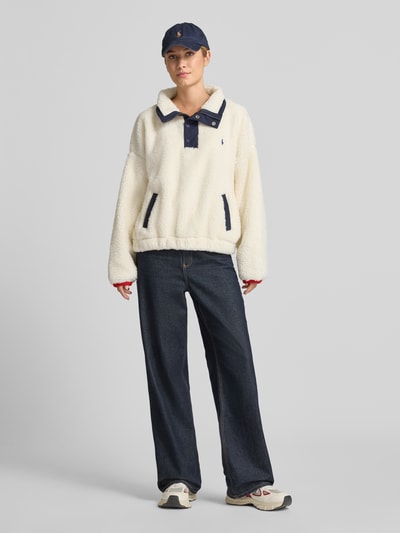Frauenmodel trägt Oversized Sweatshirt mit Polo-Bear-Intarsie von Polo Ralph Lauren, cremefarben, weiche Struktur, Dunkelblau-Details, Ganzkörperansicht von vorne, Damen Sweatshirt von Polo Ralph Lauren.