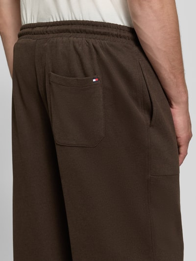 Männermodel trägt Regular Fit Sweathose aus Baumwoll-Modal-Mix von Tommy Hilfiger in Dunkelbraun, weiche Textur, Nahaufnahme Rückansicht. Herren Sweathose von Tommy Hilfiger.