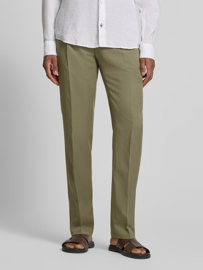 Mężczyzna nosi spodnie materiałowe Straight Fit Stoffhose aus Lyocell-Mix Modell 'Myron' von GUESS, mieszanka lyocellu i lnu, kanty, kieszenie z tyłu, zapięcie na guzik i zamek błyskawiczny, szerokość w rozmiarze 50: 42 cm, długość wewnętrzna nogawki: 107 cm, kolor jasna oliwka, gładka faktura, pełny widok z przodu.