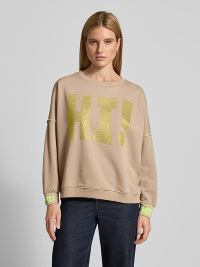 Modelka kobieca nosi Oversized Sweatshirt mit Label-Detail od miss goodlife, czysta bawełna, krój oversized, prążkowane wykończenia, okrągły dekolt, detal z logo, beż i żółty nadruk, widok całej sylwetki z przodu.