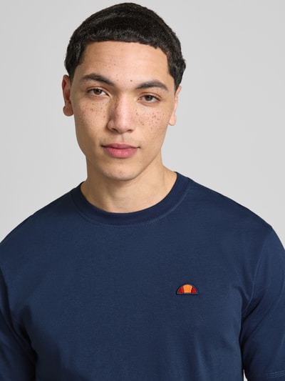 Mężczyzna nosi T-Shirt mit Label-Stitching Modell 'CASSICA' od Ellesse, granatowa bawełna, prosty krój, dekolt okrągły, zbliżenie na górną część ciała.