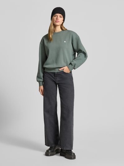 Frauenmodel trägt Sweatshirt mit Label-Stitching Modell 'CASEY' von Carhartt Work In Progress in Grün, Relaxed-Fit, Reine Baumwolle, Rundhalsausschnitt, Ganzkörperansicht von vorne.