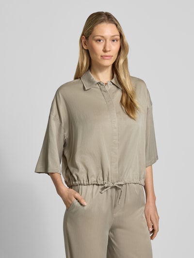 Modelka nosi Relaxed Fit Bluzkę z mieszanki modalu model 'Lainay' od Drykorn, kolor beżowy, półrękaw, tunel w dole, widok z przodu, zbliżenie na górną część ciała.