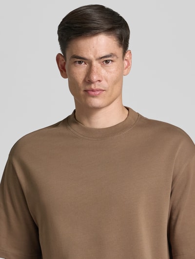 Männermodel trägt Relaxed Fit T-Shirt aus reiner Baumwolle Modell 'ASPEN' von SELECTED HOMME in Braun, glatte Textur, Nahaufnahme Oberkörper.